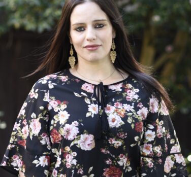 A head-and-shoulders photograph of a young woman with long brown hair and floral patterned top.