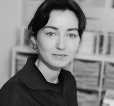 A black and white close-up photograph of a woman with dark hair and a small smile