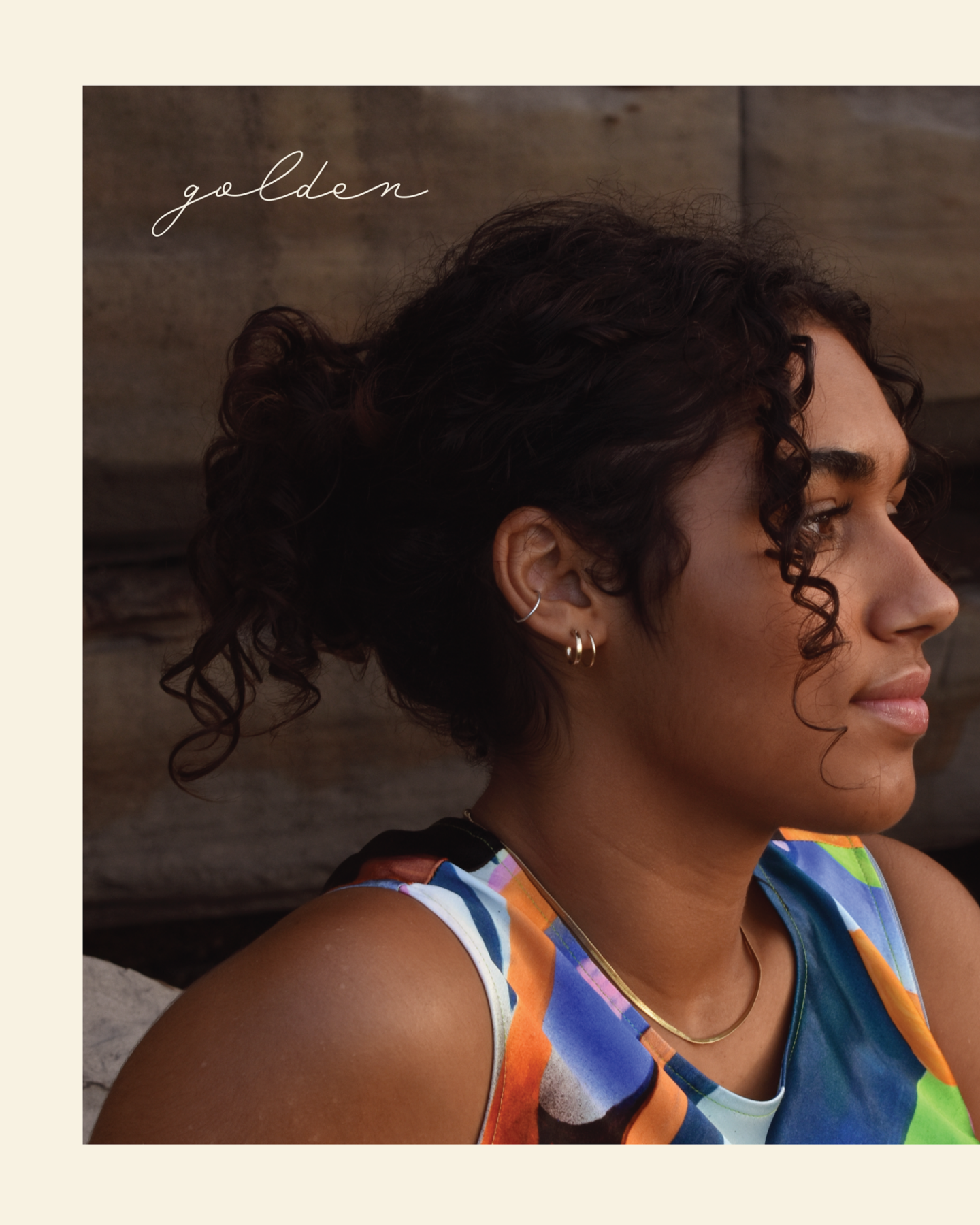 An album cover featuring a photograph of a young woman in profile, with dark skin and curly black hair worn up, and three small gold hoop earrings